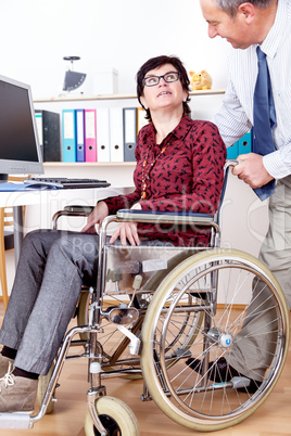 Man helps a wheelchair user in the office
