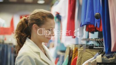 young, pretty business woman chooses clothes in shop