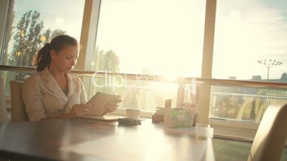 young beautiful business woman sitting at a table with tablet in hands