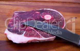 raw meat with knife on kitchen board