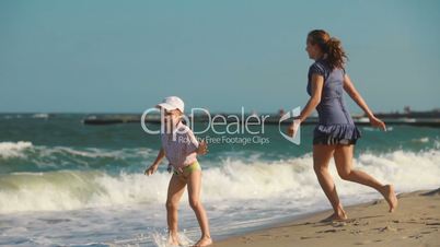 Mom and young son wet his feet in the sea, laugh and run away