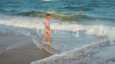 little boy jumping over the waves and running on the beach
