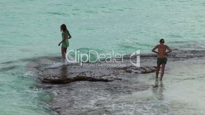 2 girls moisten his feet in the Caribbean Sea. Cuba, Cayo Largo