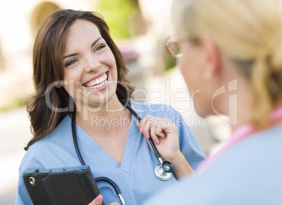 Two Young Adult Female Doctors or Nurses Talking Outside