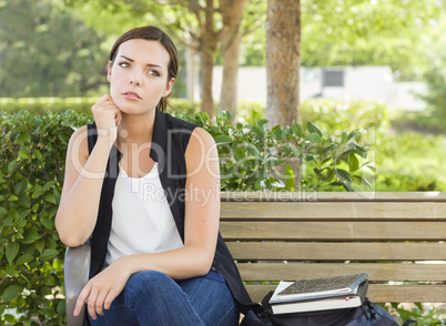 Melancholy Young Adult Woman Sitting on Bench Next to Books.