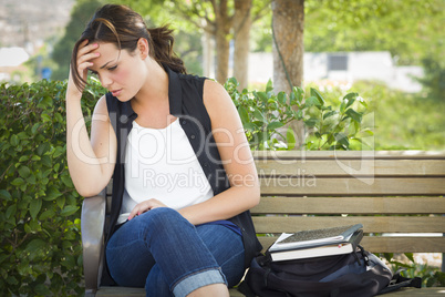 Upset Young Woman Sitting Alone on Bench Next to Books
