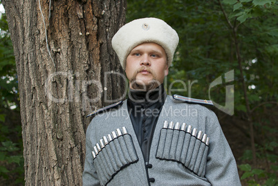 Young man in a cossack clothes in a forest