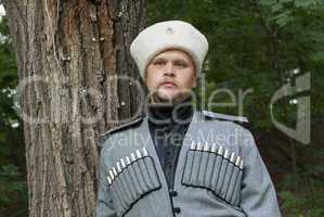 Young man in a cossack clothes in a forest