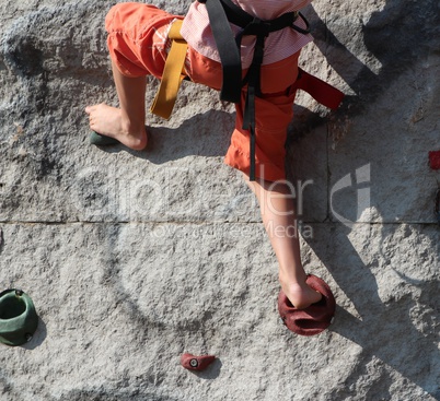 Kind klettert an einem Kletterfelsen