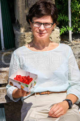 Woman holding small strawberry cake in the box