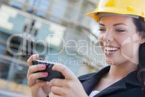 Female Contractor Wearing Hard Hat on Site Texting with Phone