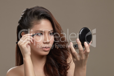female asian applying eye liner