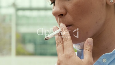 Business woman smoking cigarette near office building