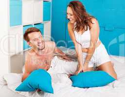 young couple having fun with pillows at home