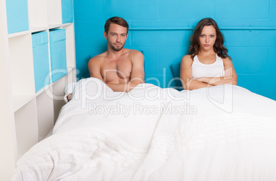 pessimistic couple having an argument sitting on bed
