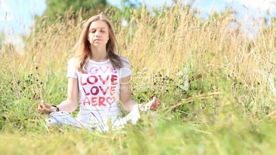 Young girl in white meditating in the city park