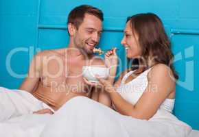 wife feeding her husband breakfast in bed