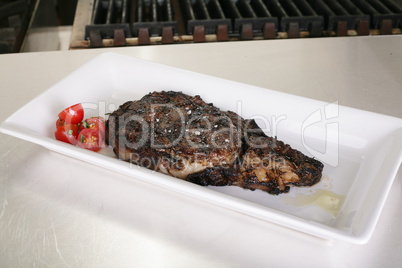 Rib-eye steak resting on the plate in the kitchen ready to serve