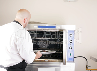 chef putting a tray of a juicy steak in a professional oven