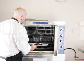 chef putting a tray of a juicy steak in a professional oven