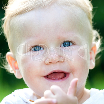 Cheerful baby girl on the summer meadow