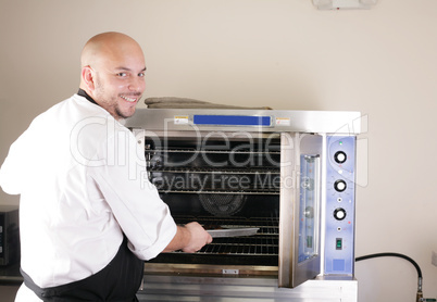 Happy young chef cooking steak in the oven