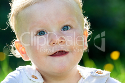 Cheerful baby girl on the summer meadow