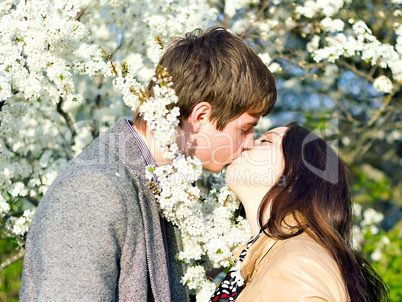 spring outdoor portrait of a young couple kissing