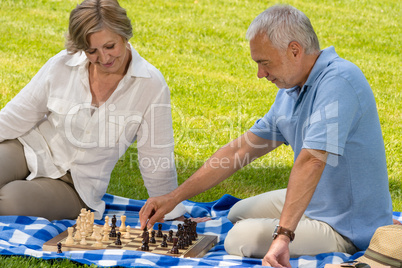 Retired senior couple playing chess in park