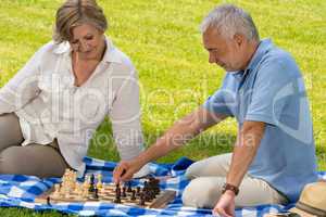 Retired senior couple playing chess in park