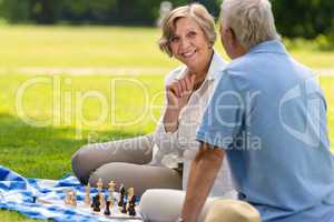 Senior wife and husband playing chess outdoors