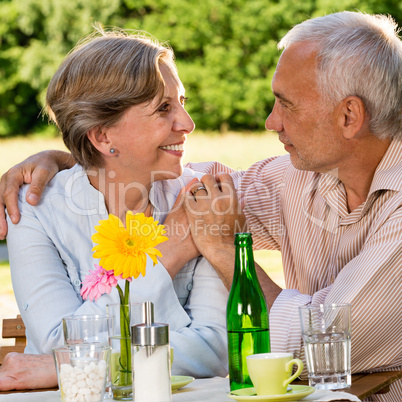 Retired couple sitting at table holding hands