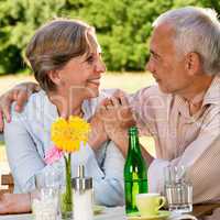 Retired couple sitting at table holding hands