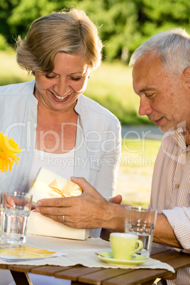 Elderly married couple opening present