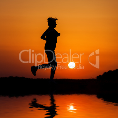 Silhouette woman running against orange sunset