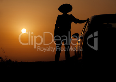 Silhouette woman with hat standing near car