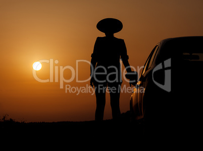 Silhouette woman with hat standing near car