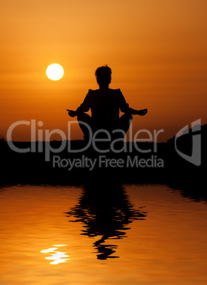 Silhouette woman sitting and relaxing against orange sunset