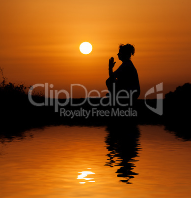 Silhouette woman sitting and relaxing against orange sunset