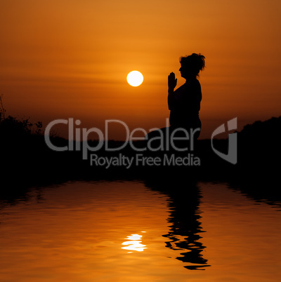 Silhouette woman sitting and relaxing against orange sunset