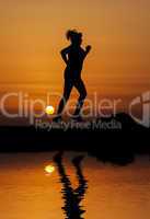 Silhouette woman running against orange sunset