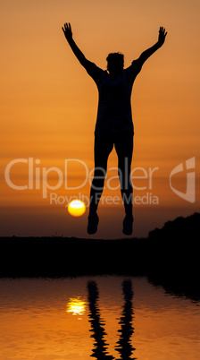 Silhouette woman jumping against orange sunset