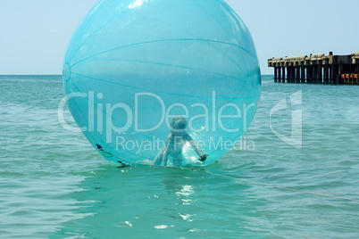 little girl inside a giant balloon on the sea surface