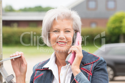 Seniorin an Telefonzelle