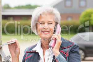 Seniorin an Telefonzelle