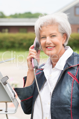 Seniorin an Telefonzelle