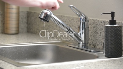 Man turns off dripping kitchen sink faucet