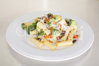 Rigatoni with vegetables served on a white plate.