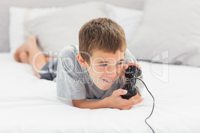 Little boy lying on bed playing video games