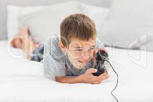 Little boy lying on bed playing video games